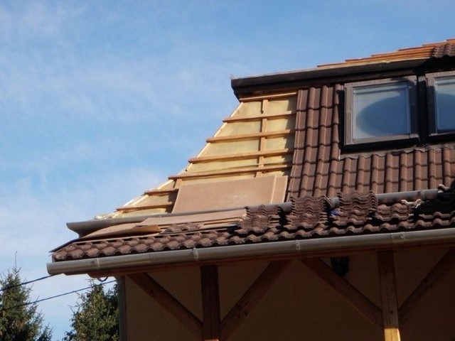 A tetőcserepek megbontása a hangszigetelő rétegek elhelyezésének érdekében.